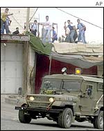 Palestinian schoolchildren throw stones at an Israeli tank